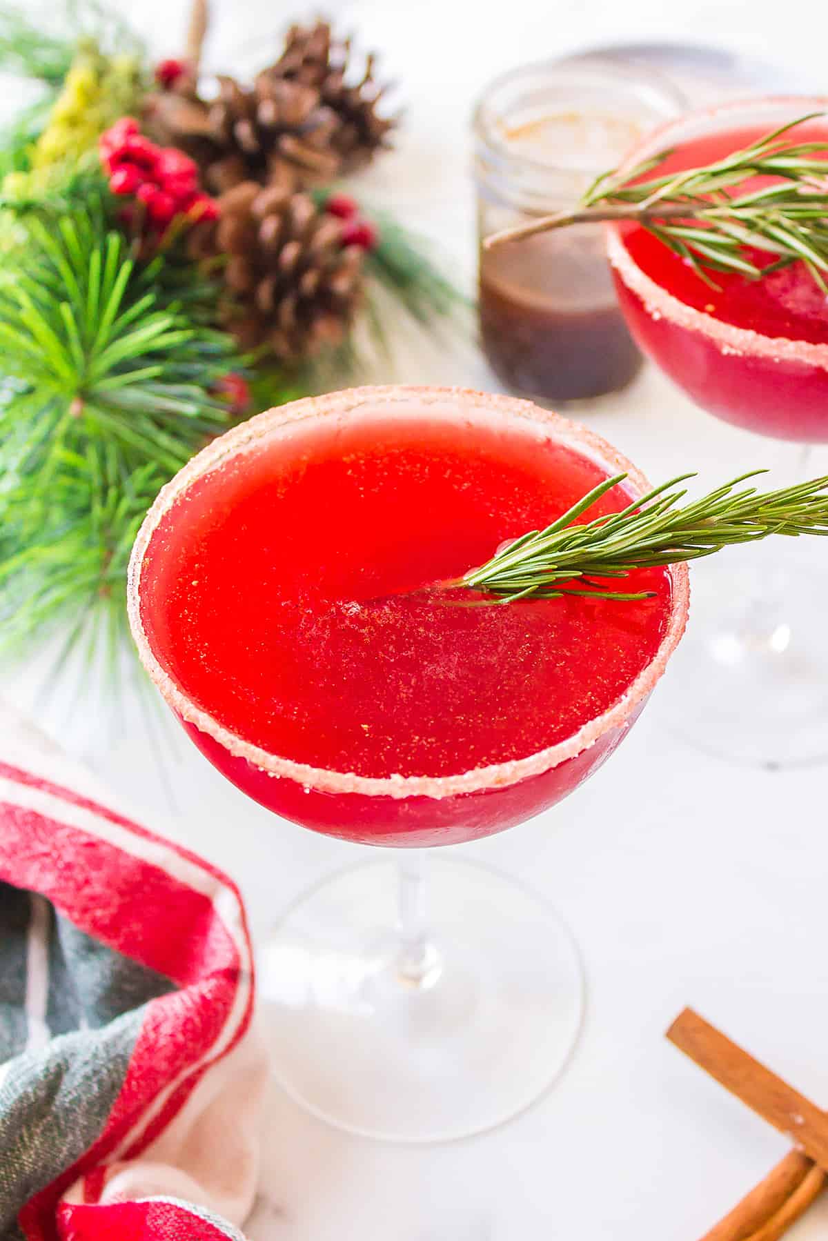 Cranberry cocktail in glass with sprig of rosemary.