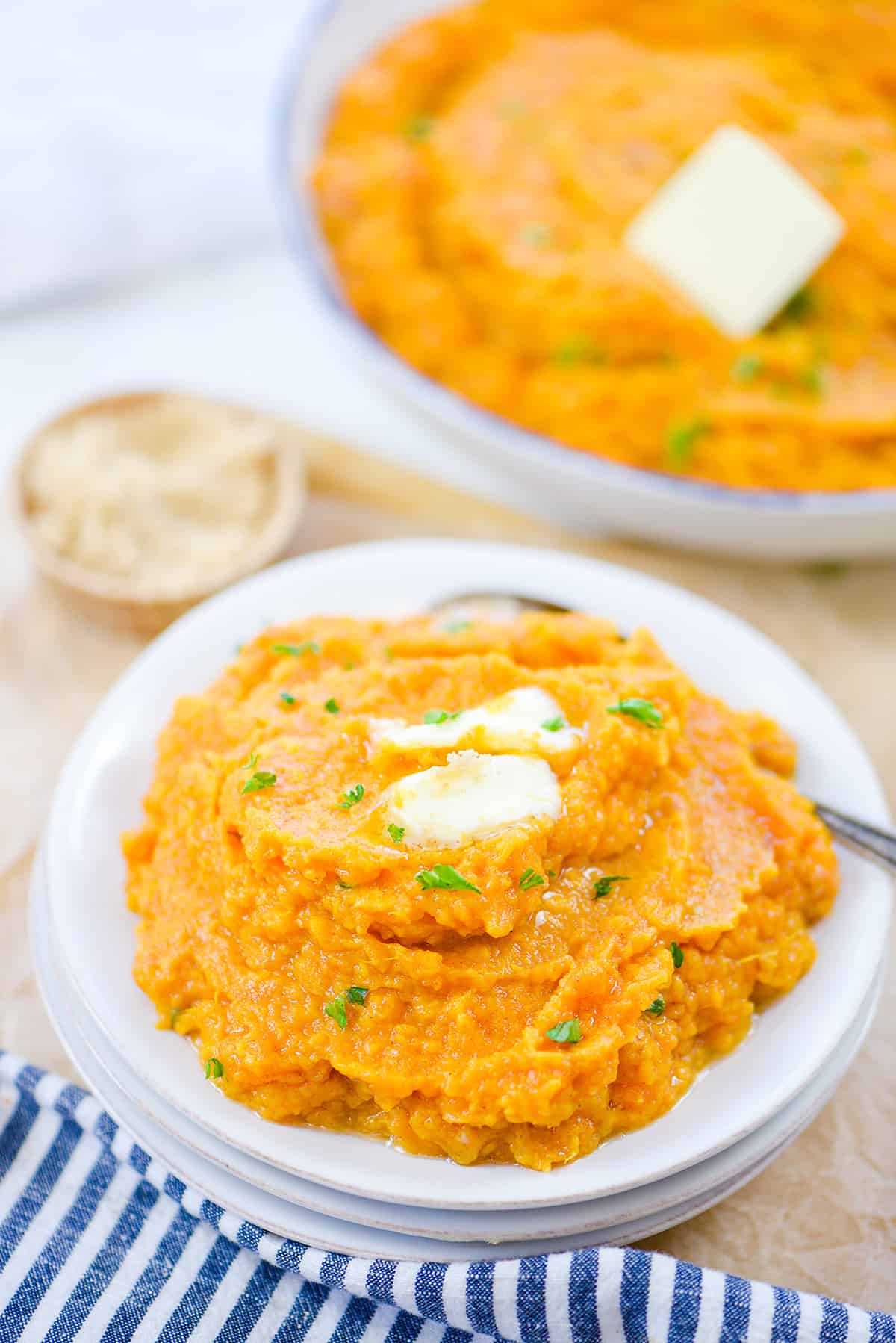 Stack of white plates topped with sweet potato mash.