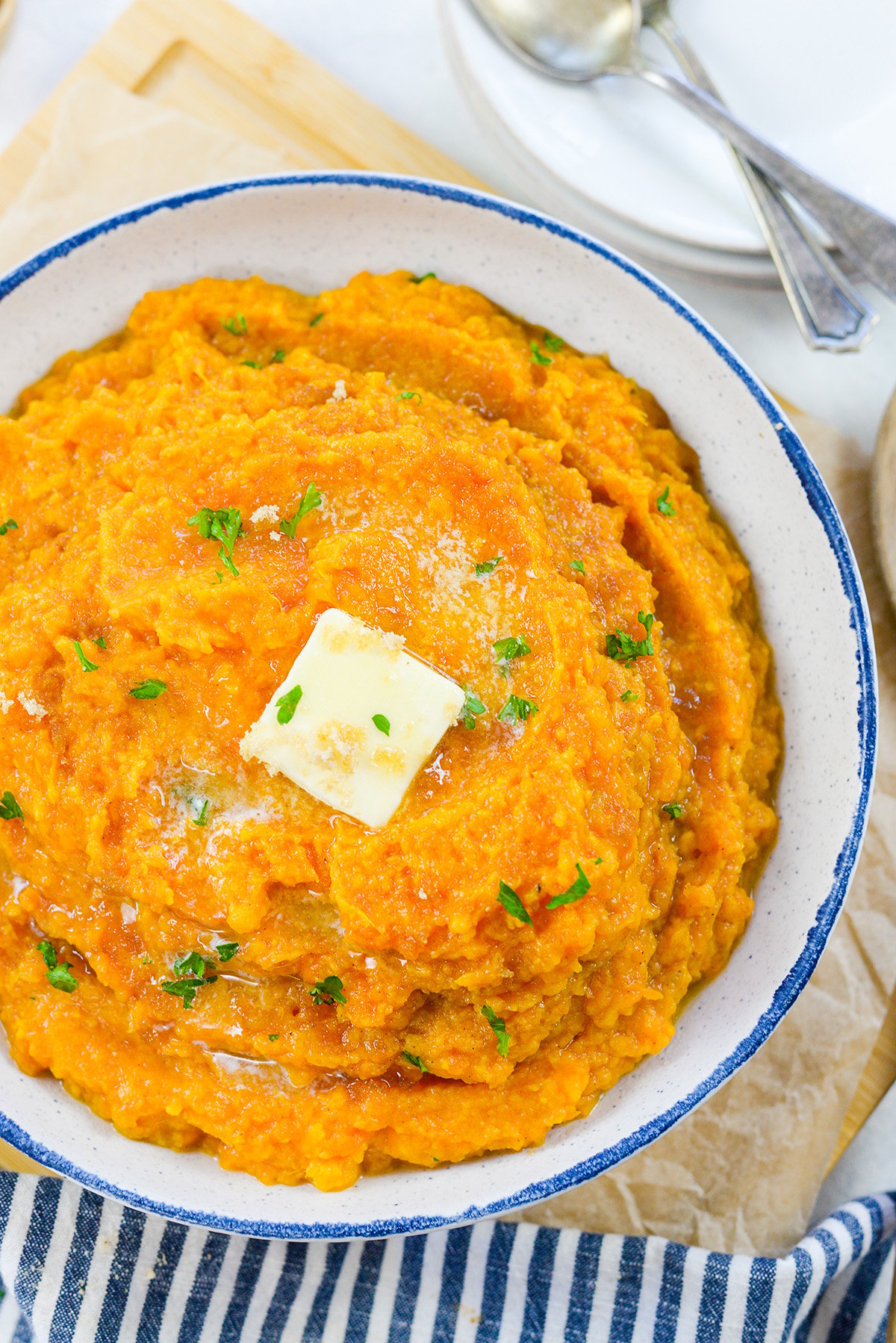 Mashed sweet potatoes in bowl with butter on top.