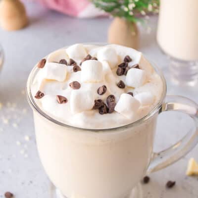 Creamy white hot chocolate in glass mug.