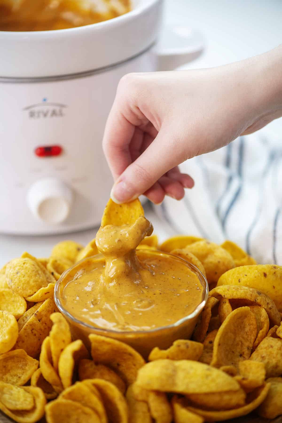 Hand dipping a Frito into chili cheese dip.