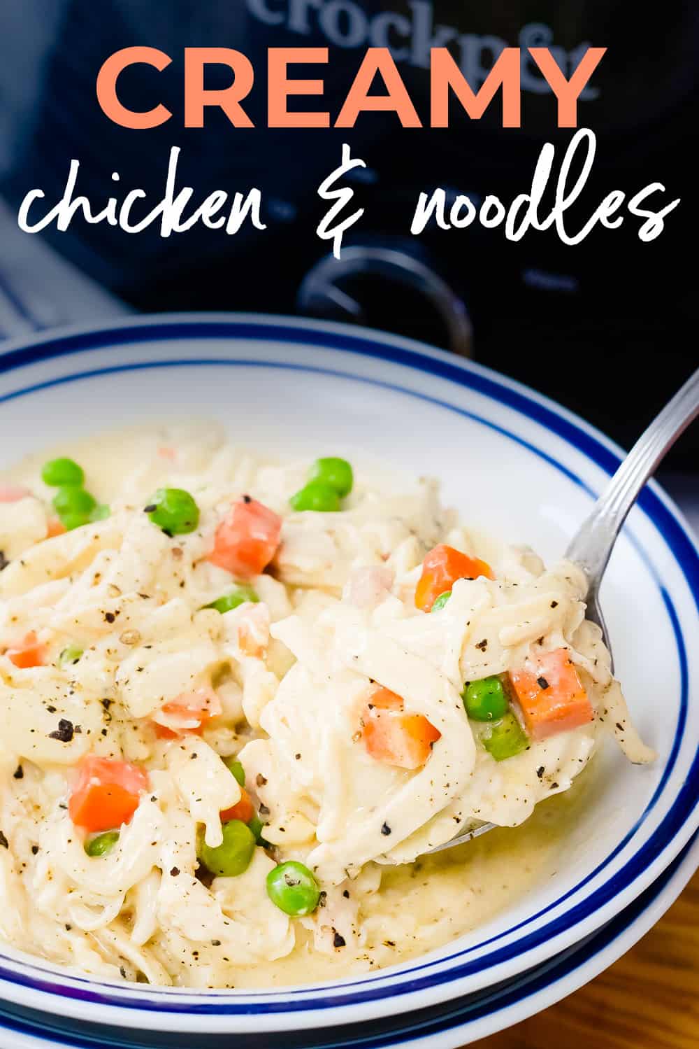 Creamy crockpot chicken and noodles on spoon over bowl.