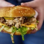 Woman holding a Big Mac sloppy joe sandwich in her hands.