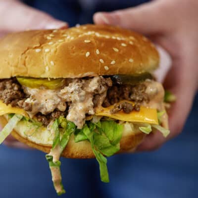 Woman holding a Big Mac sloppy joe sandwich in her hands.