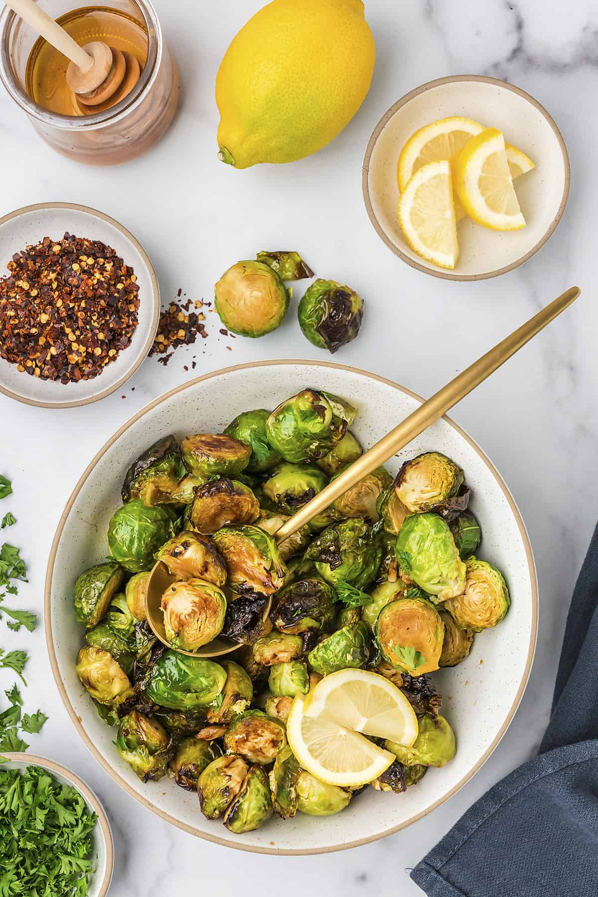 Air fried brussels sprouts in white bowl with gold spoon.