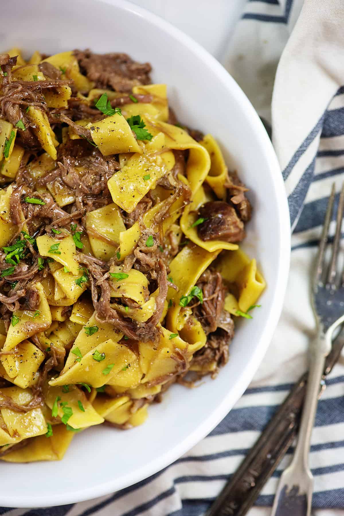 Overhead view of beef and noodles in white bowl.