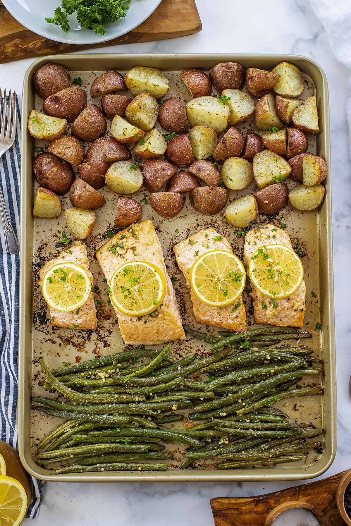 Overhead view of sheet pan with salmon, potatoes, and green beans.