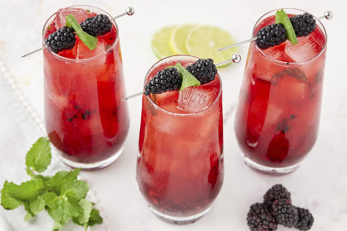 Mojitos made with mint and blackberries in glasses.