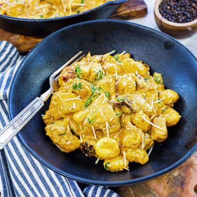 Tuscan chicken and gnocchi recipe in black bowl.