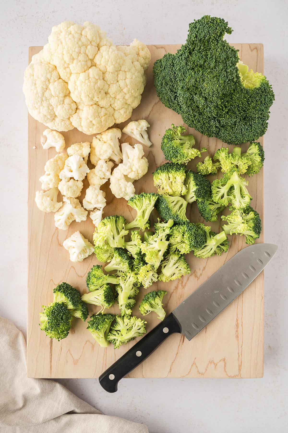 Broccoli and cauliflower on cutting board with knife.