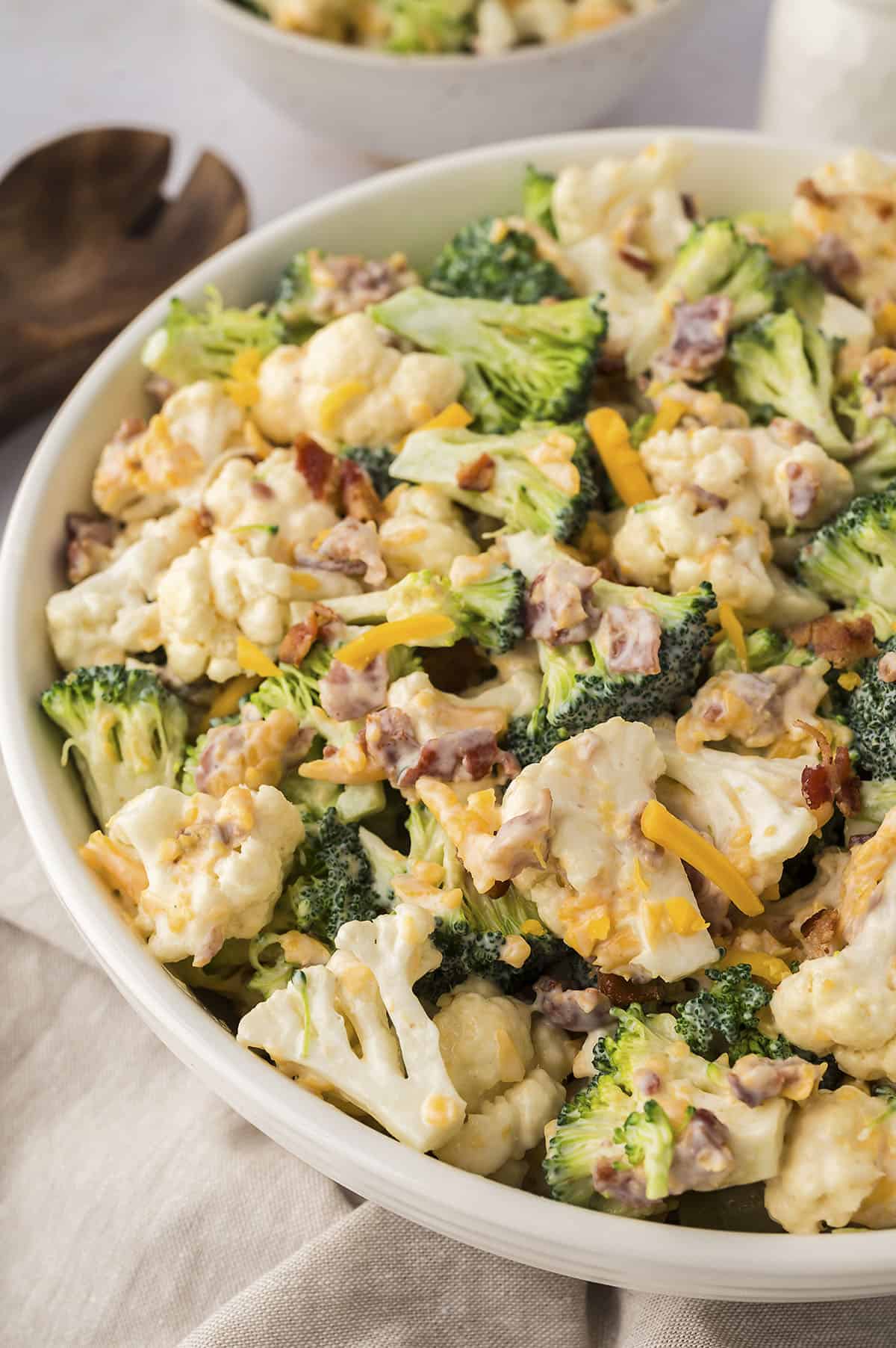 Bowl full of Amish broccoli salad with cauliflower, cheese, and bacon.