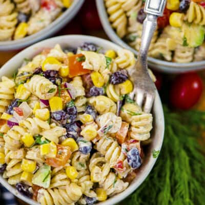 Pasta salad in white bowl with fork.