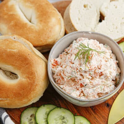 Smoked salmon cream cheese spread in bowl surrounded by bagels.