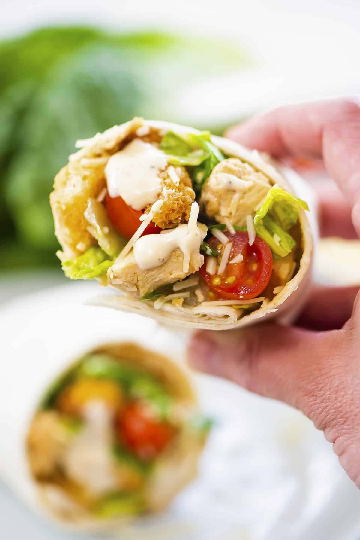 Hand holding a chicken caesar wrap.