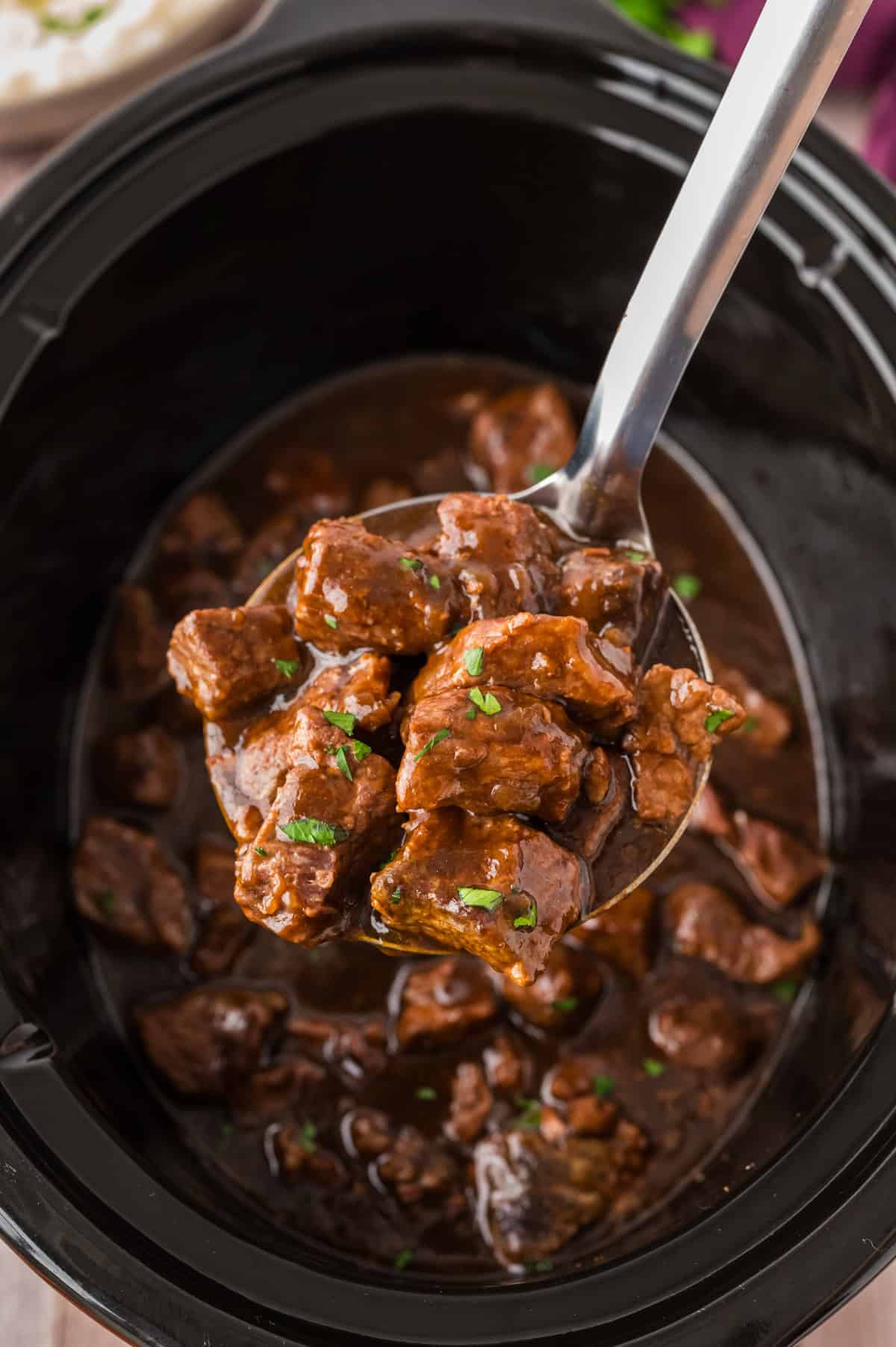 Beef tips and gravy in crockpot on ladle.