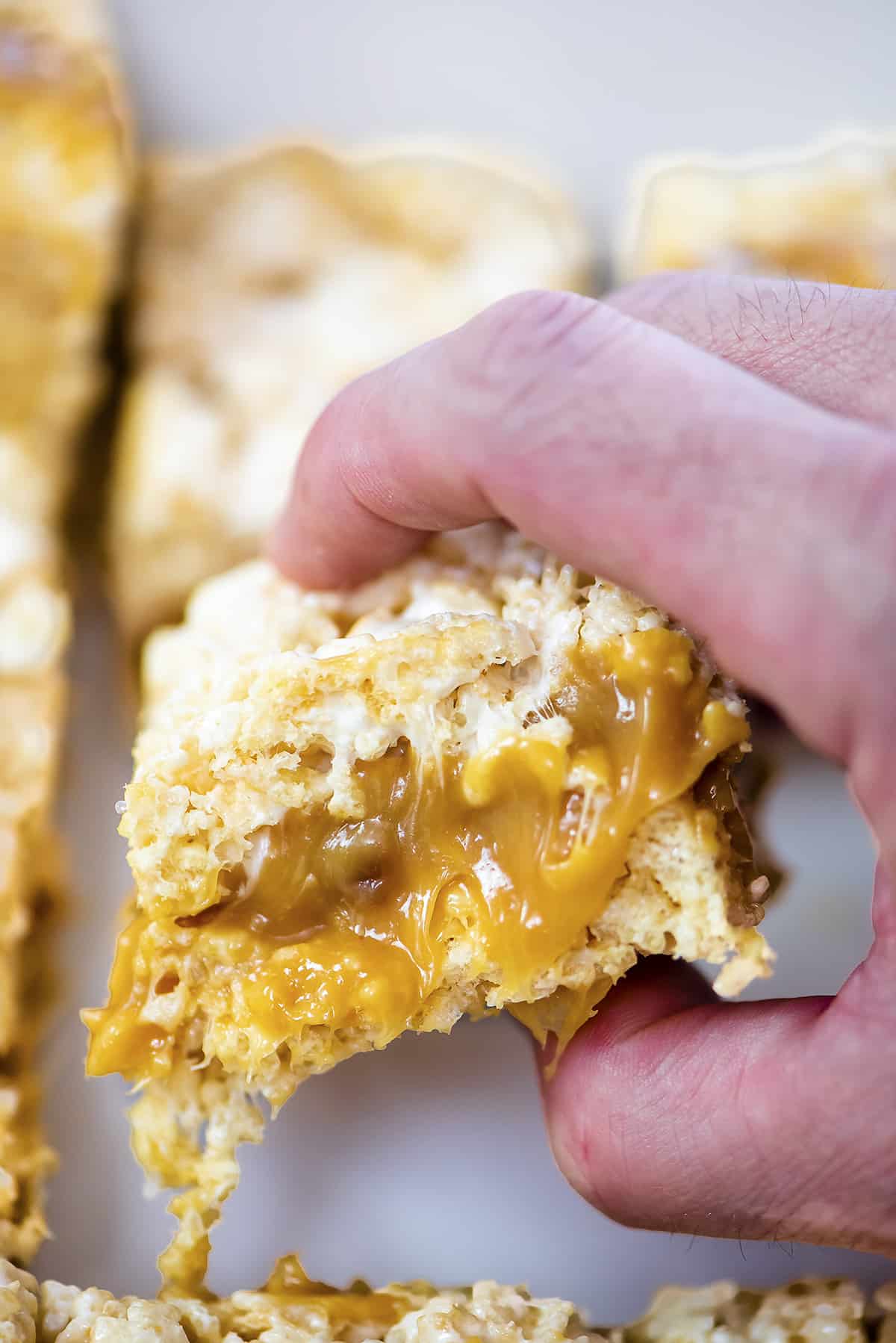 Hand grabbing a caramel rice krispies treat.