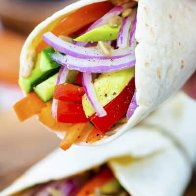 Hand holding a hummus wrap.