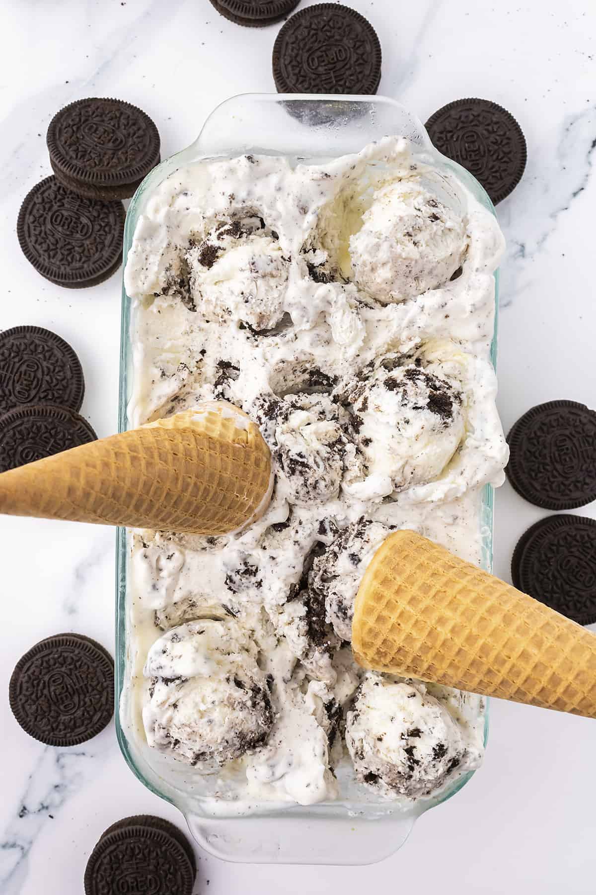 Overhead view of ice cream with cones stuck in it.