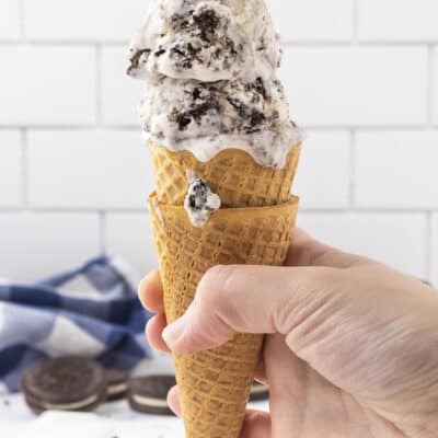 Hand holding a cone full of cookies and cream ice cream.
