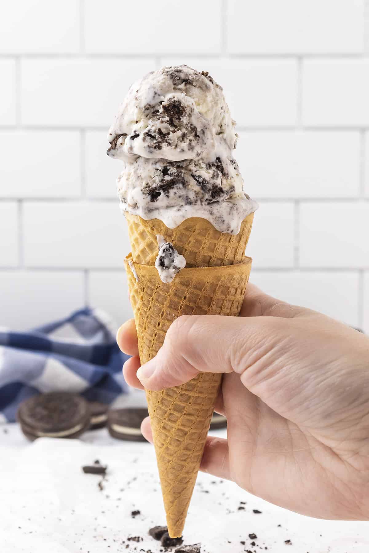 Hand holding a cone full of cookies and cream ice cream.