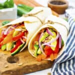 Hummus veggie wraps on wooden board.