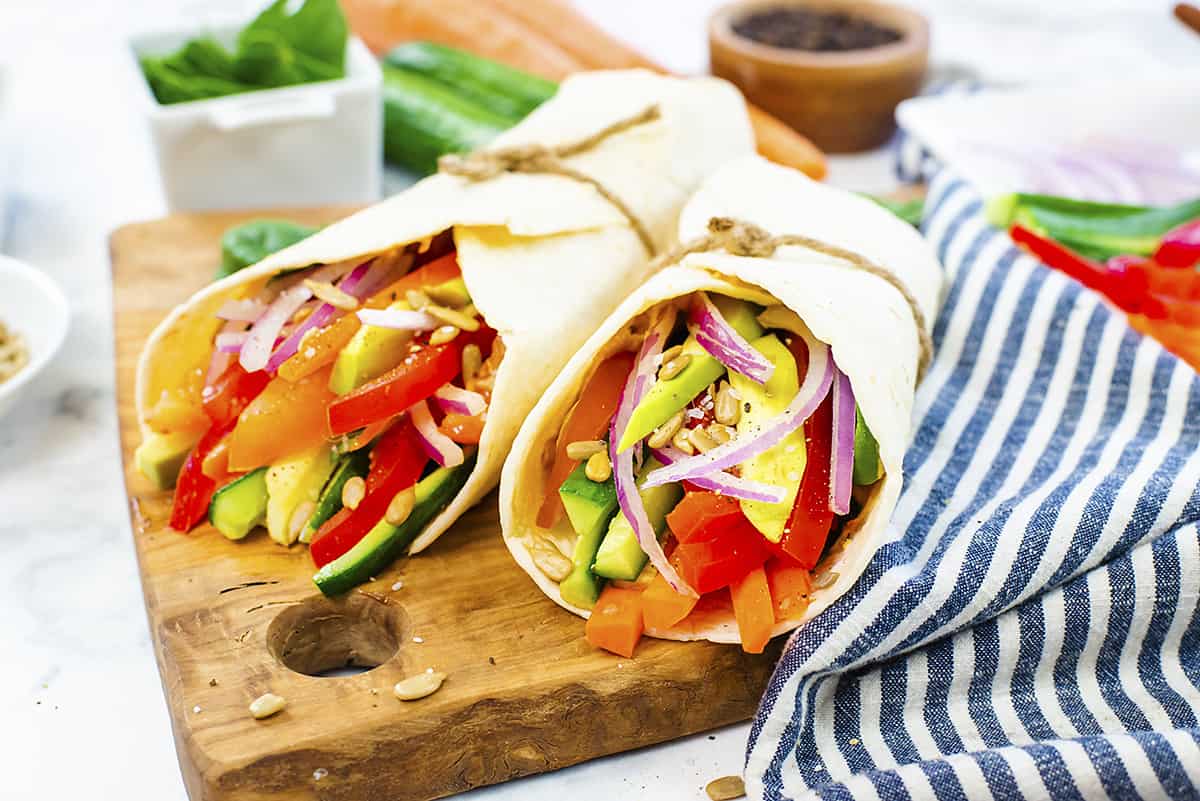 Hummus veggie wraps on wooden board.