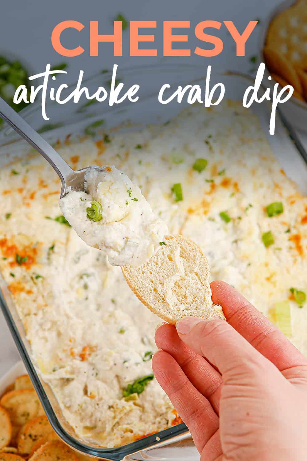 Artichoke dip with crab being spooned onto bread.