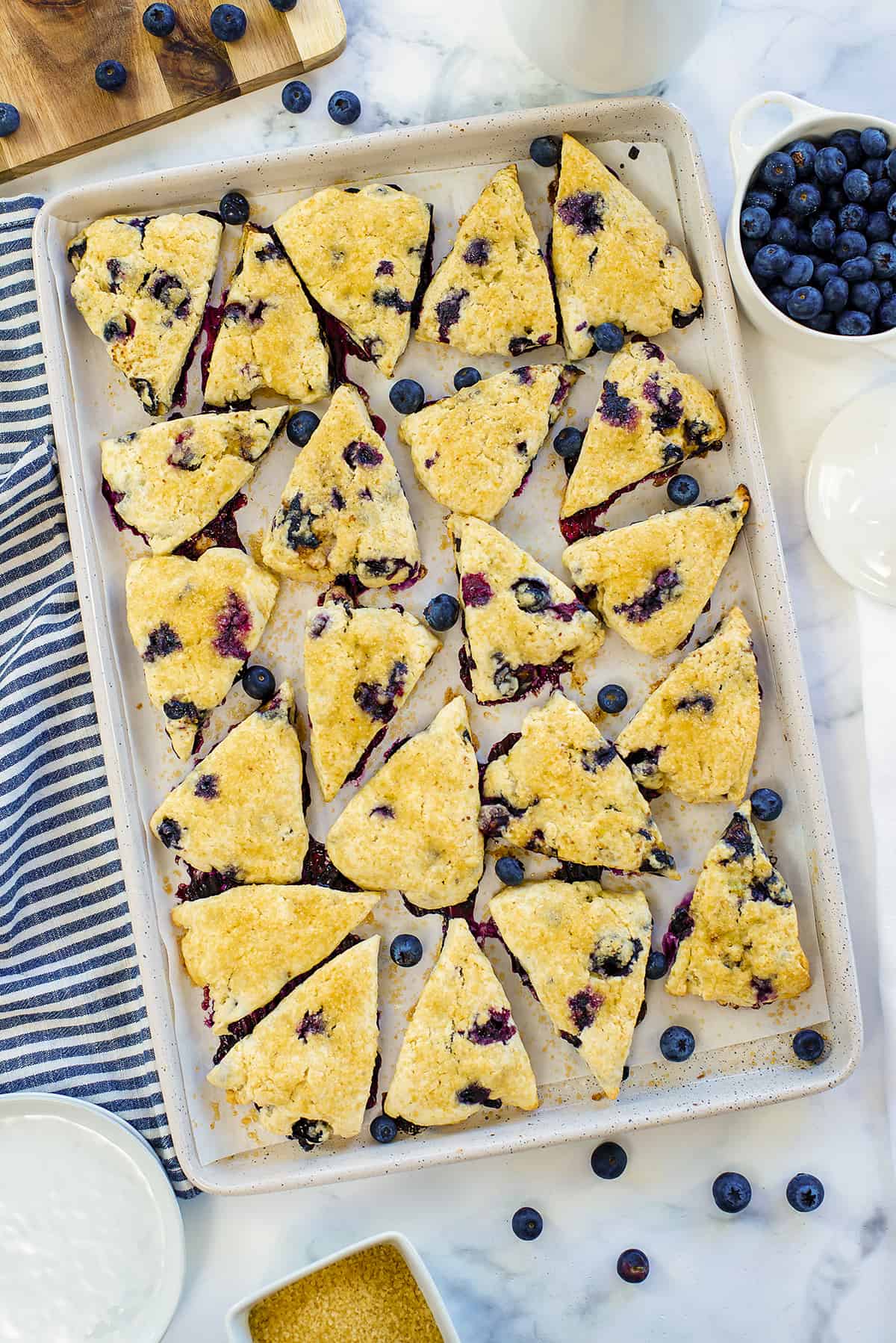 Baked scones studded with fresh blueberries on baking sheet.