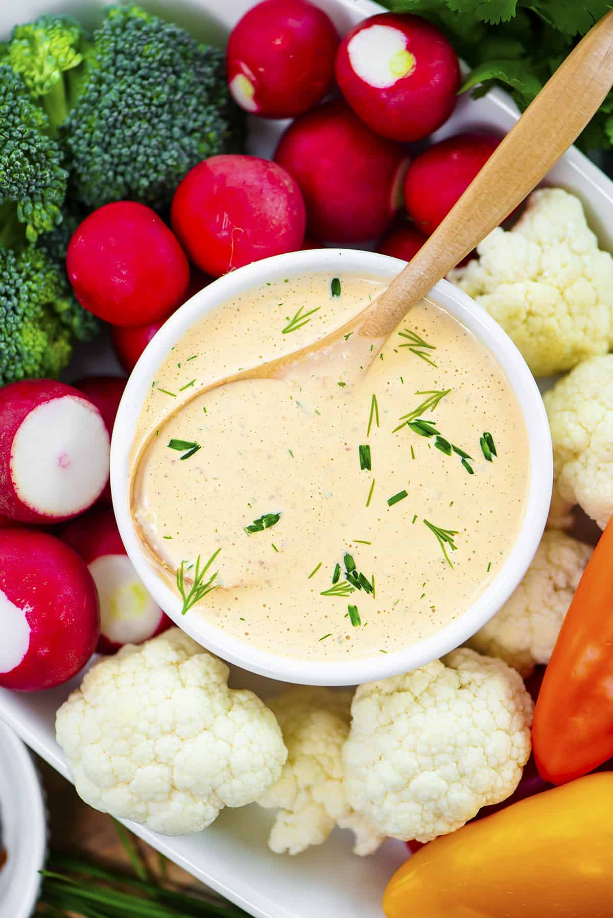 Chipotle ranch dressing in bowl surrounded by fresh vegetables.