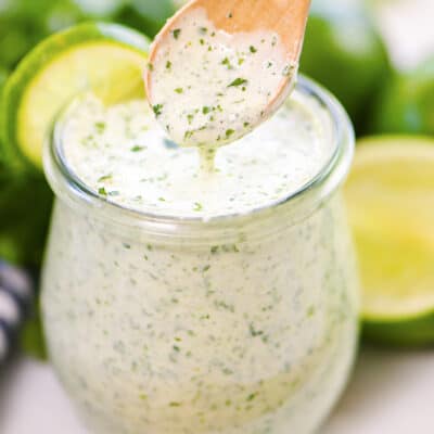 Spoon being dipped in a jar of cilantro lime dressing.