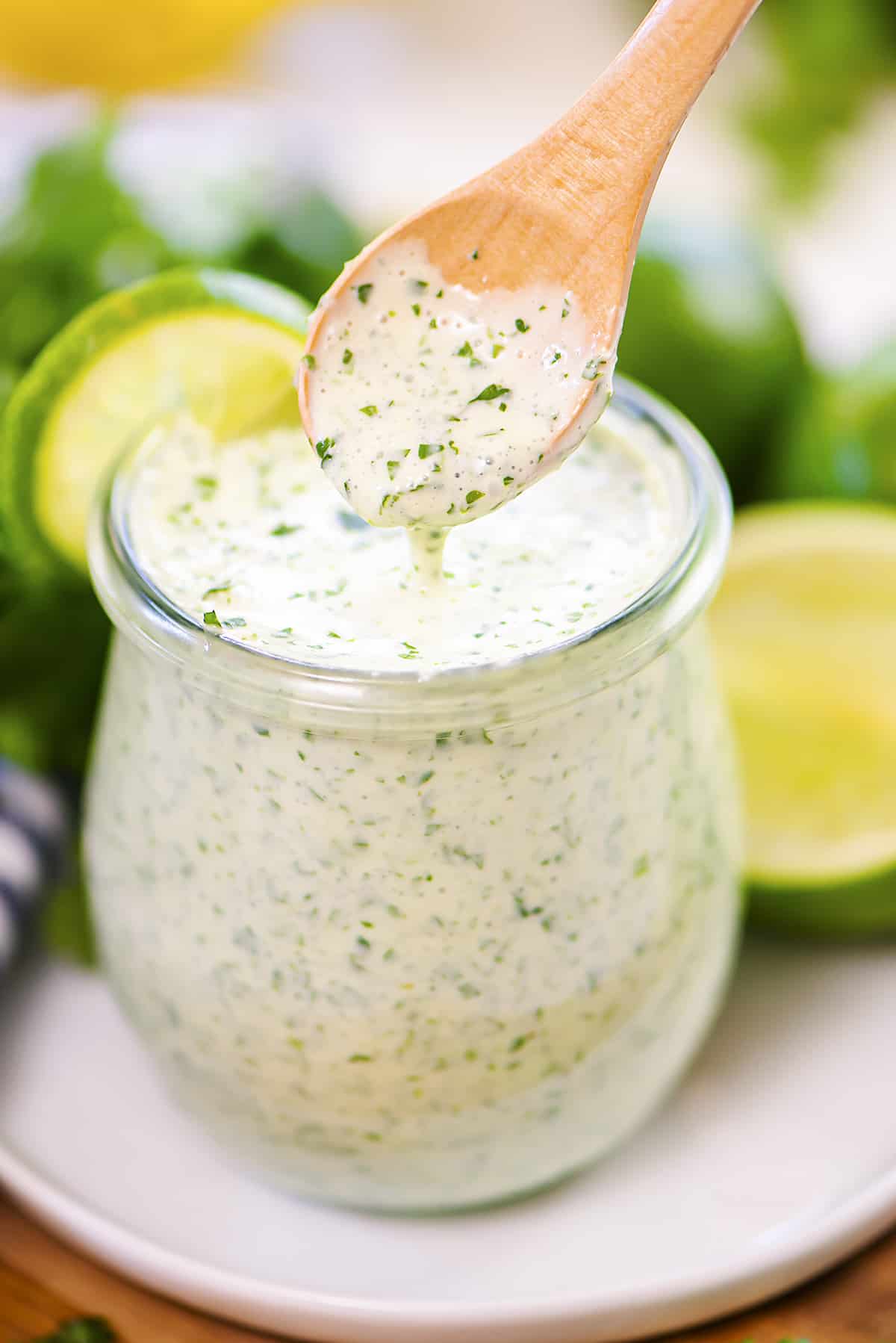Spoon being dipped in a jar of cilantro lime dressing.