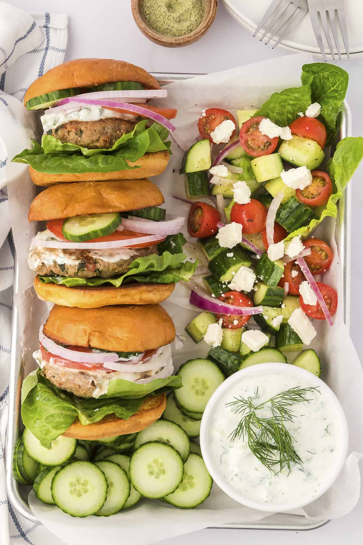 Overhead view of Greek turkey burgers on tray with Greek vegetable salad.