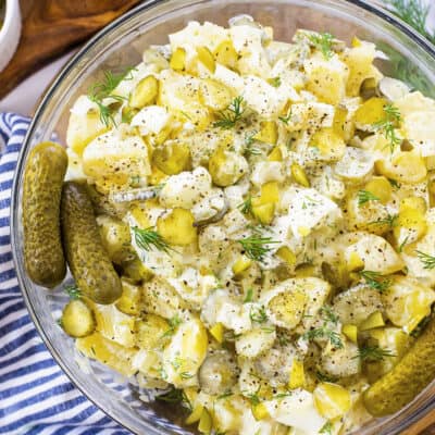 Overhead view of dill pickle potato salad in glass bowl.