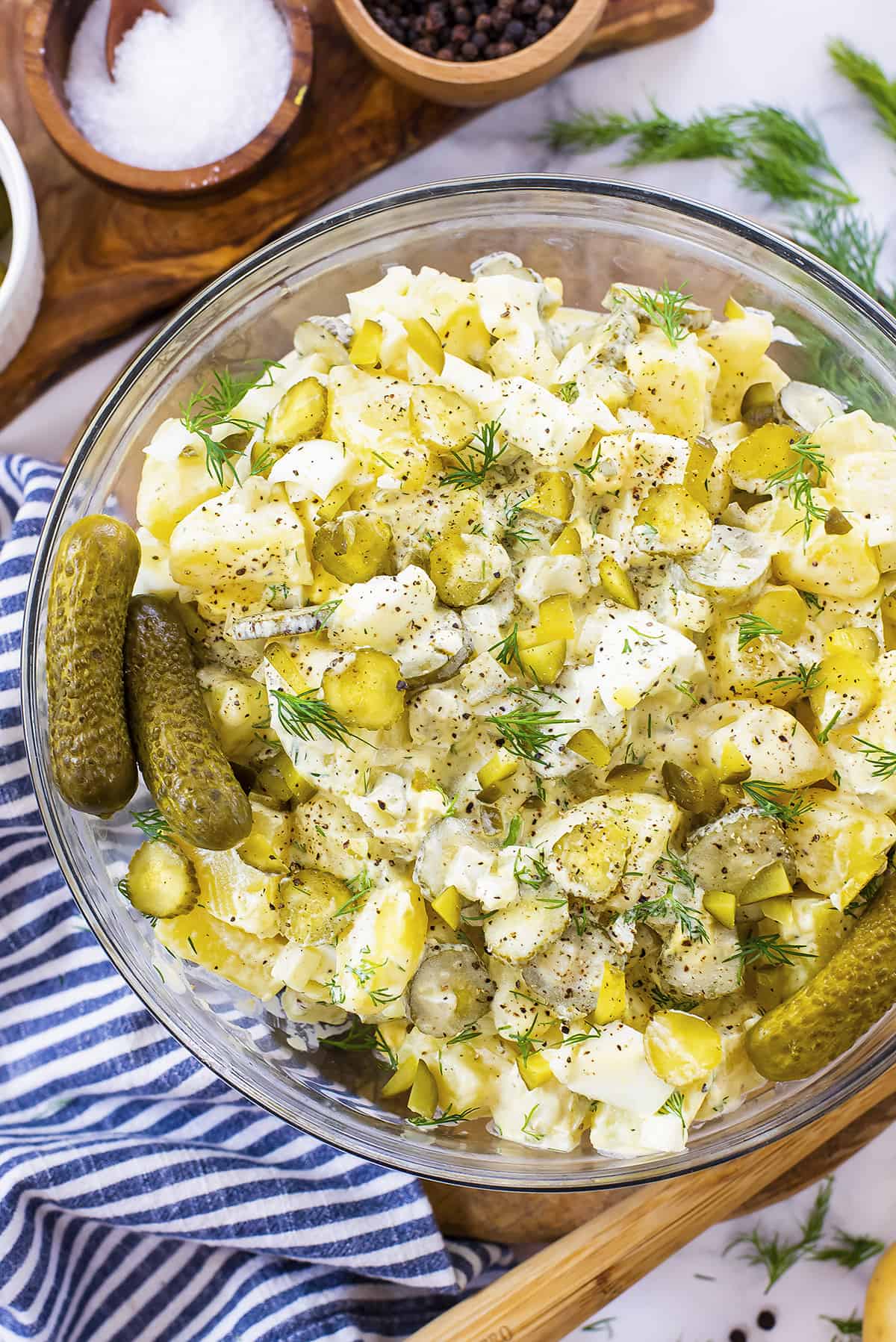 Overhead view of dill pickle potato salad in glass bowl.