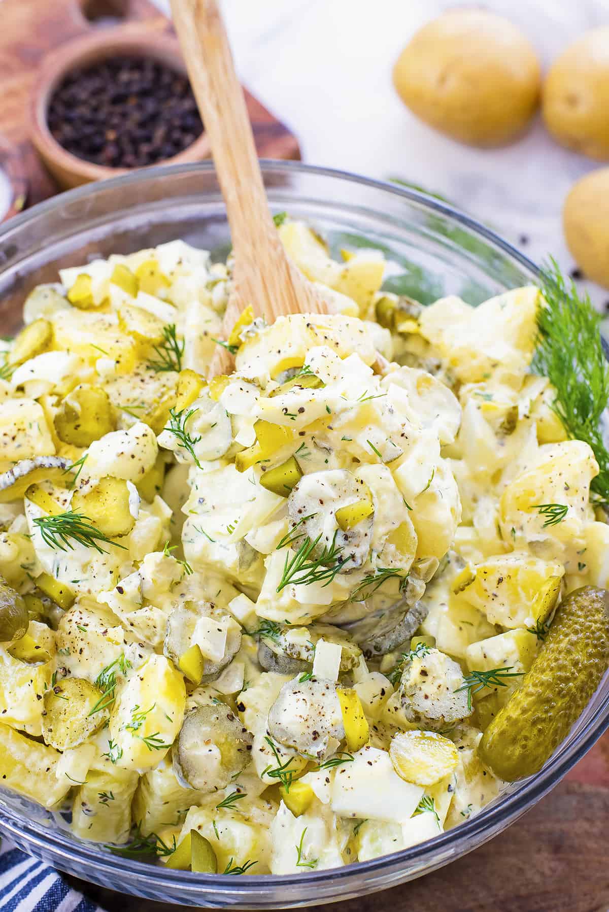 Potato salad with dill pickles in glass bowl.