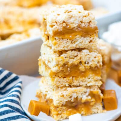Stack of rice krispies treats filled with caramel on plate.