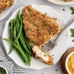 Pretzel crusted chicken on white plate.