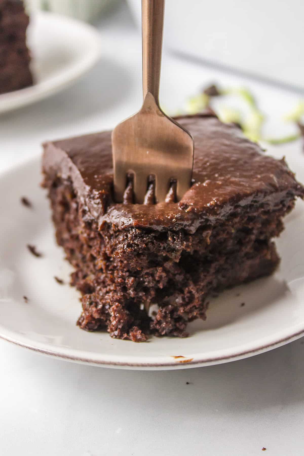 Slice of chocolate zucchini cake with a fork in it.