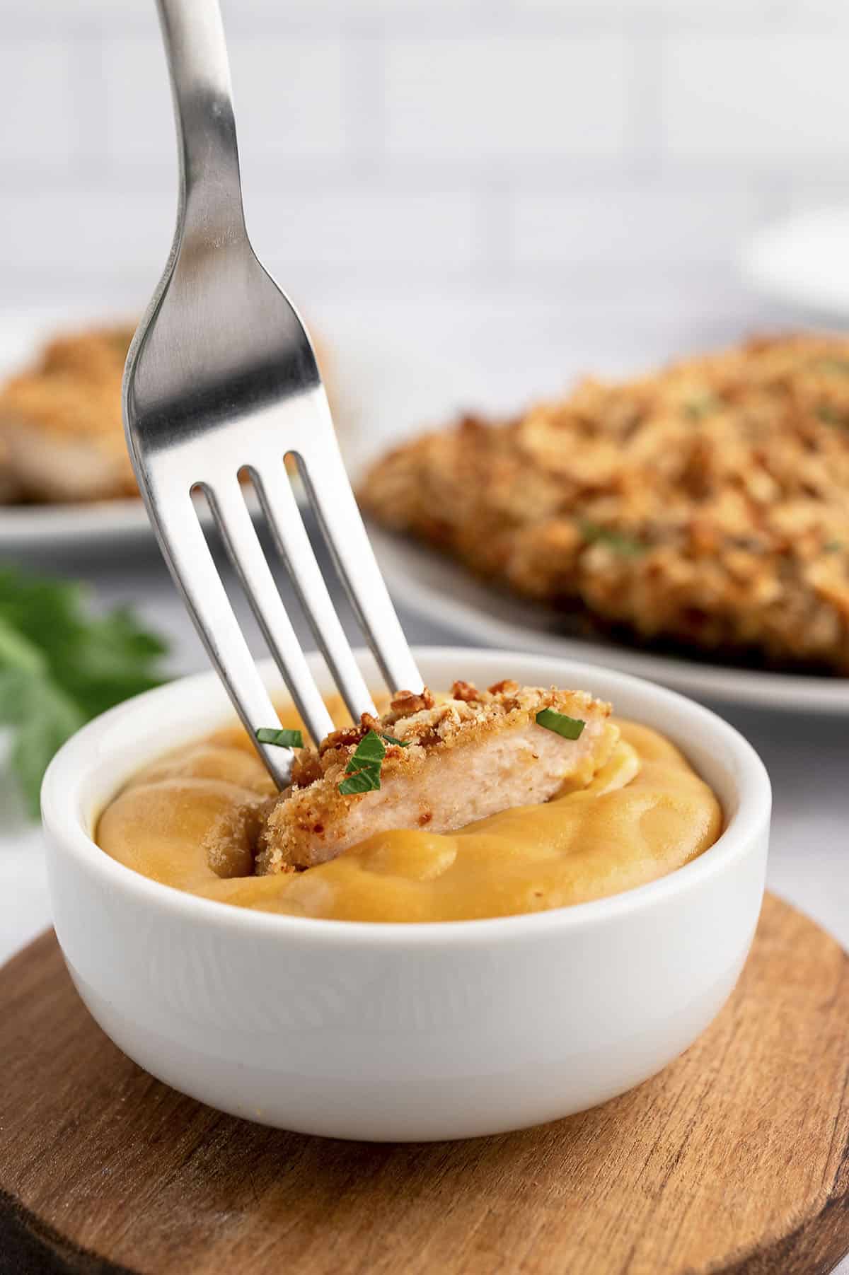 Pretzel crusted chicken being dipped in homemade honey mustard.