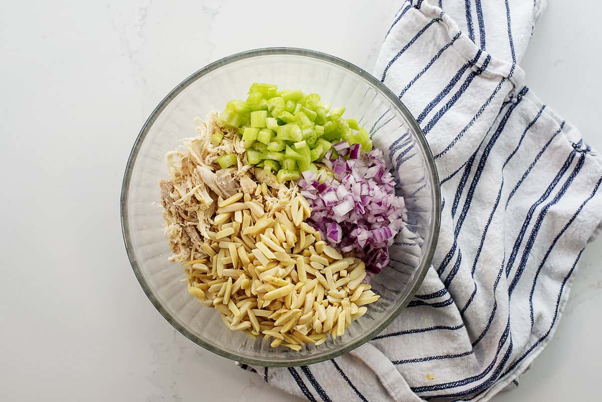 Chicken salad ingredients in glass mixing bowl.