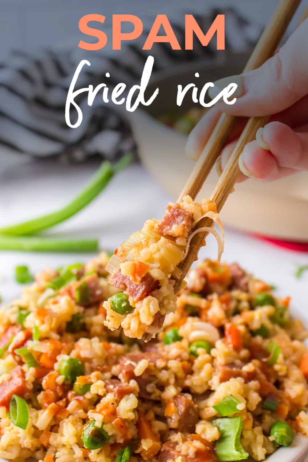 Hand using chopsticks to scoop up fried rice.