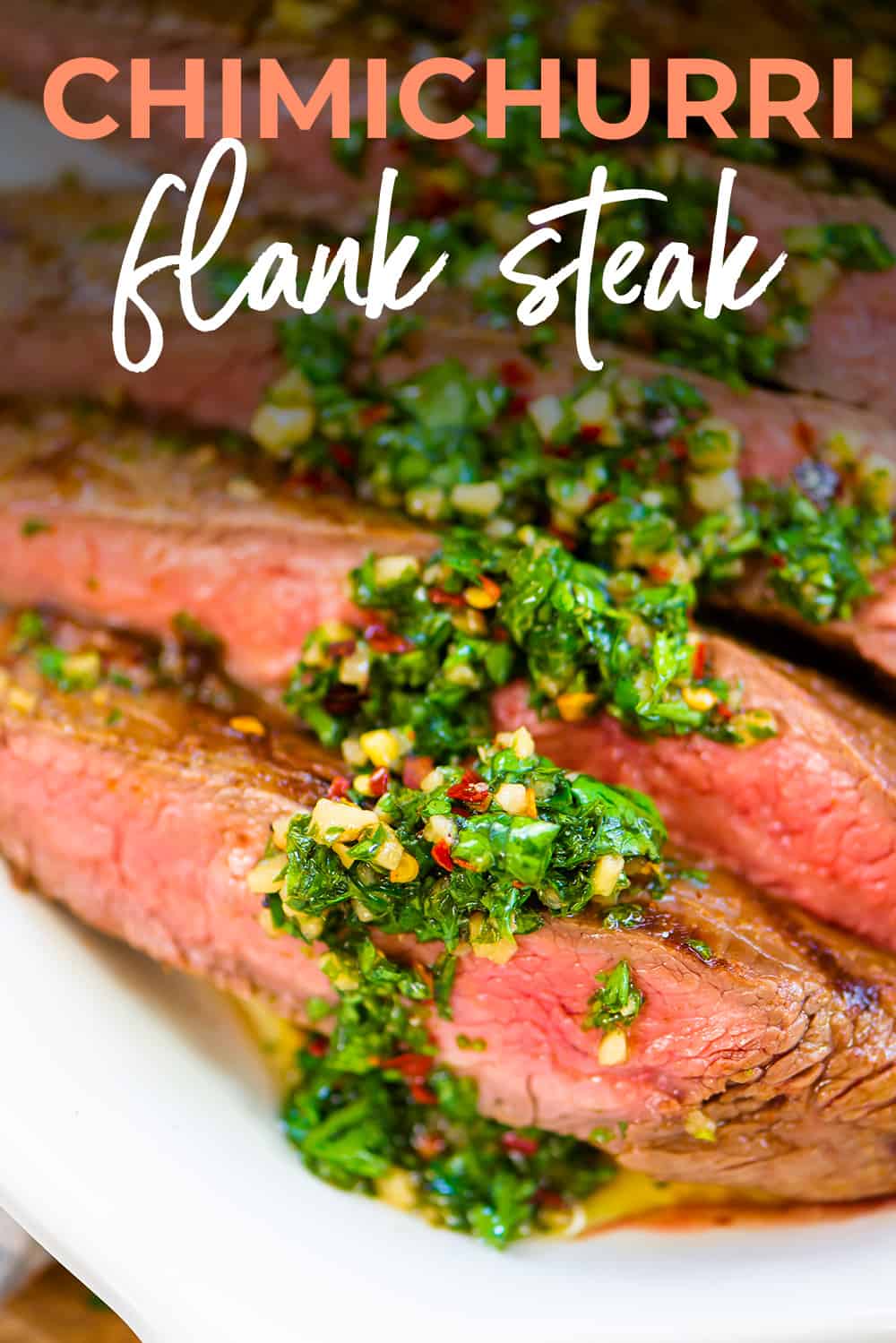 Close up of sliced flank steak with chimichurri drizzled over the top.
