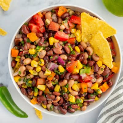 Cowboy caviar recipe in white bowl with chips.