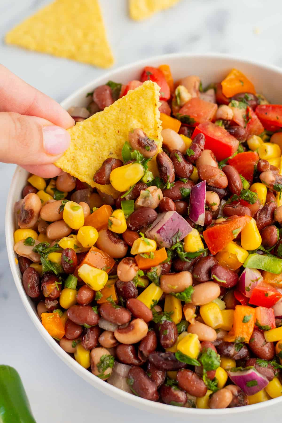 Hand dipping a chip into cowboy caviar.
