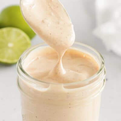 Creamy chipotle sauce dripping off spoon into jar.
