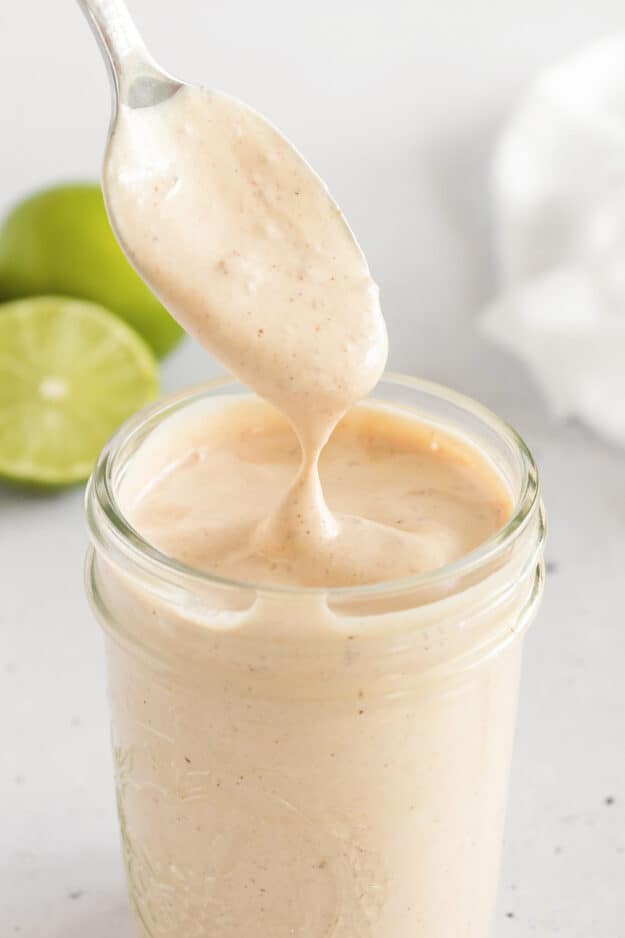 Creamy chipotle sauce dripping off spoon into jar.