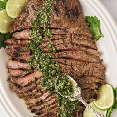 Flank steak with chimichurri on platter.