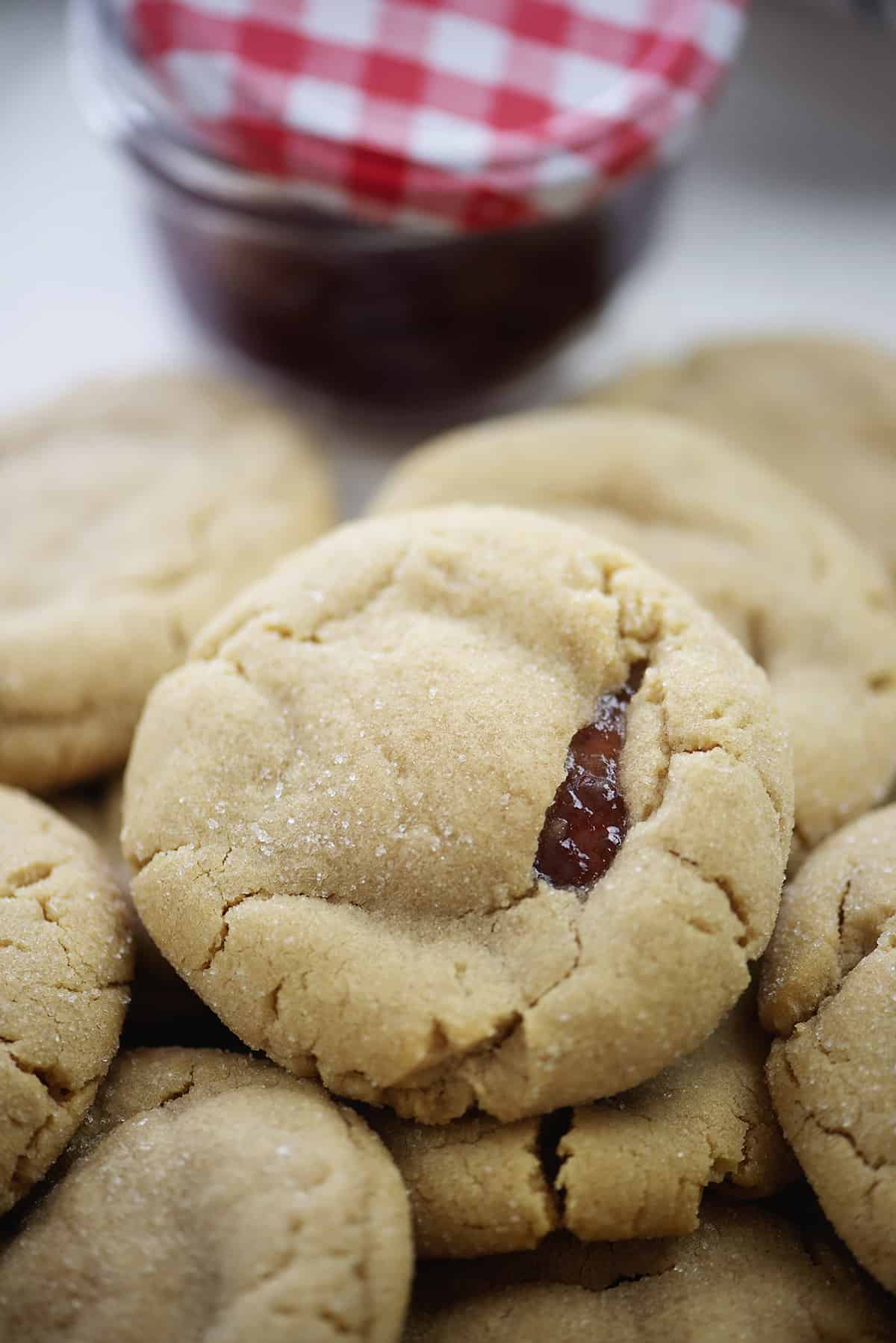 Baked peanut butter and jelly stuffed cookies piled on baking sheet.