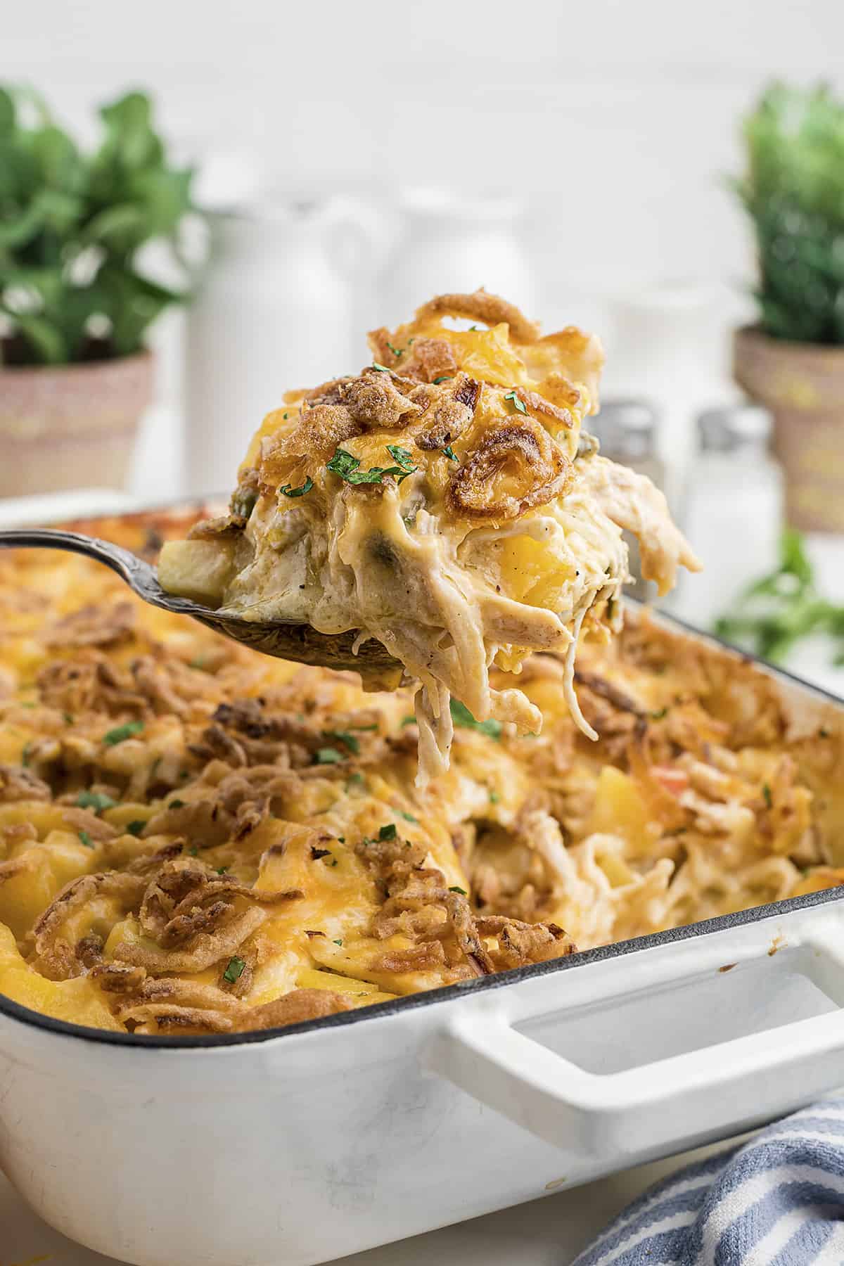 Scoop of chicken potato casserole being taken out of baking dish.