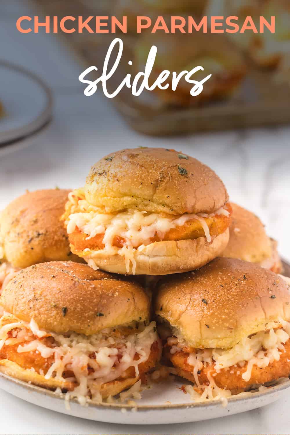 Chicken parmesan sliders stacked on a plate.